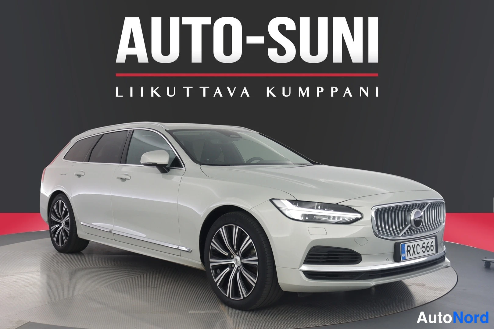 Etuviisto, nokka oikealle: Valkoinen farmariauto vinosti etu kolmannesvasemmalle kuvakulmassa studiotaustaa vasten.