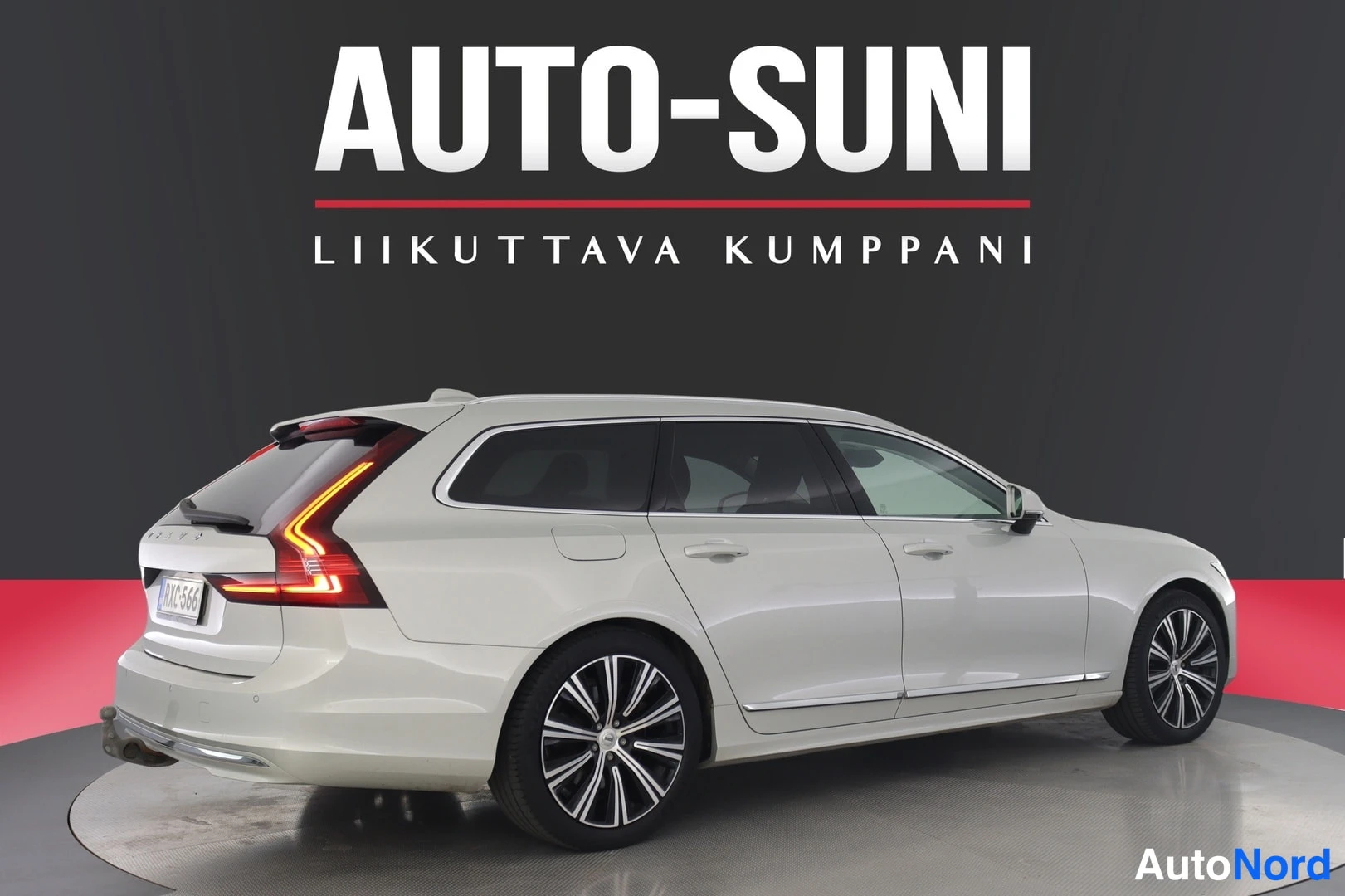 Takaviisto: Valkoinen farmariauto takaa vinosti kuvakulmassa studiotaustaa vasten.