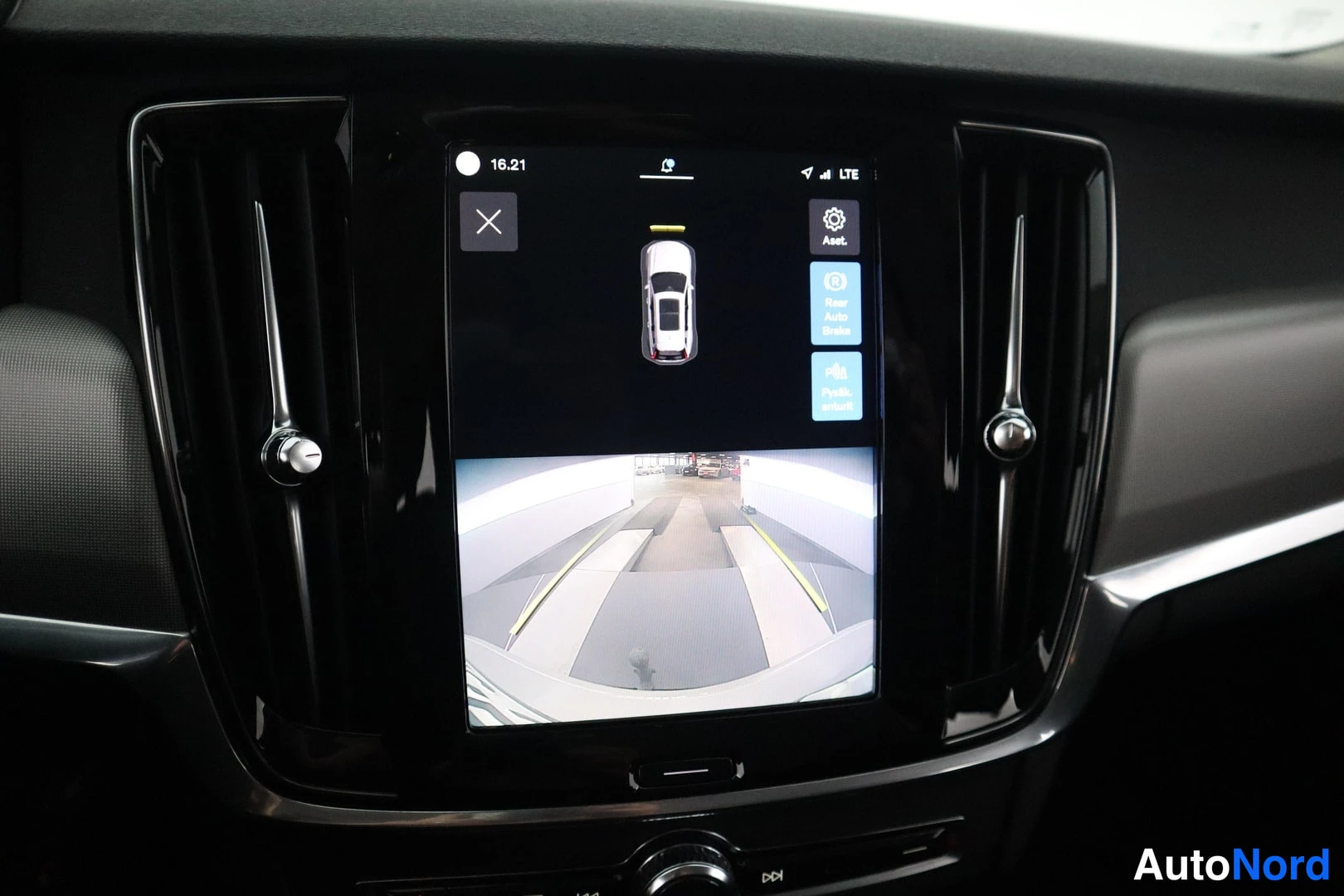 Muu: Autoinfotainment-näyttö näyttää pysäköintikameran kuvan ja ajoneuvon yläkuvan, lisäksi ilmastointi- ja asetusvalikot.