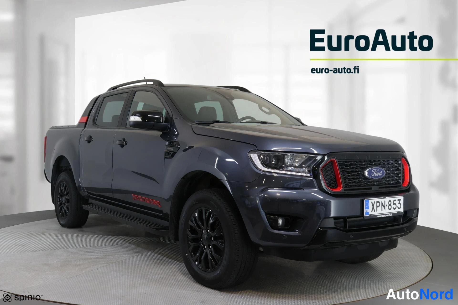 Etuviisto, nokka oikealle: Ford Ranger -nutta-auto tummanharmaana etuviistosta oikealta, rekisteritunnus, mustat kevytmetallivanteet ja katutaso rungossa.