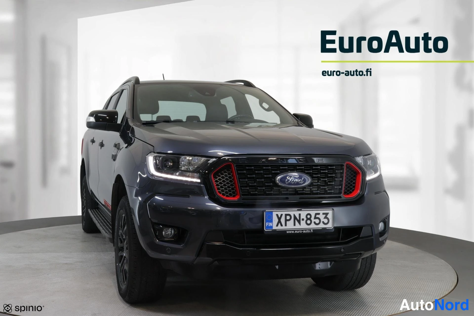 Edestä: Ford Ranger -nutta-auto suoraan edestä, tummanharmaa kori, mustat kevytmetallivanteet ja punakoristettu etusäleikkö.