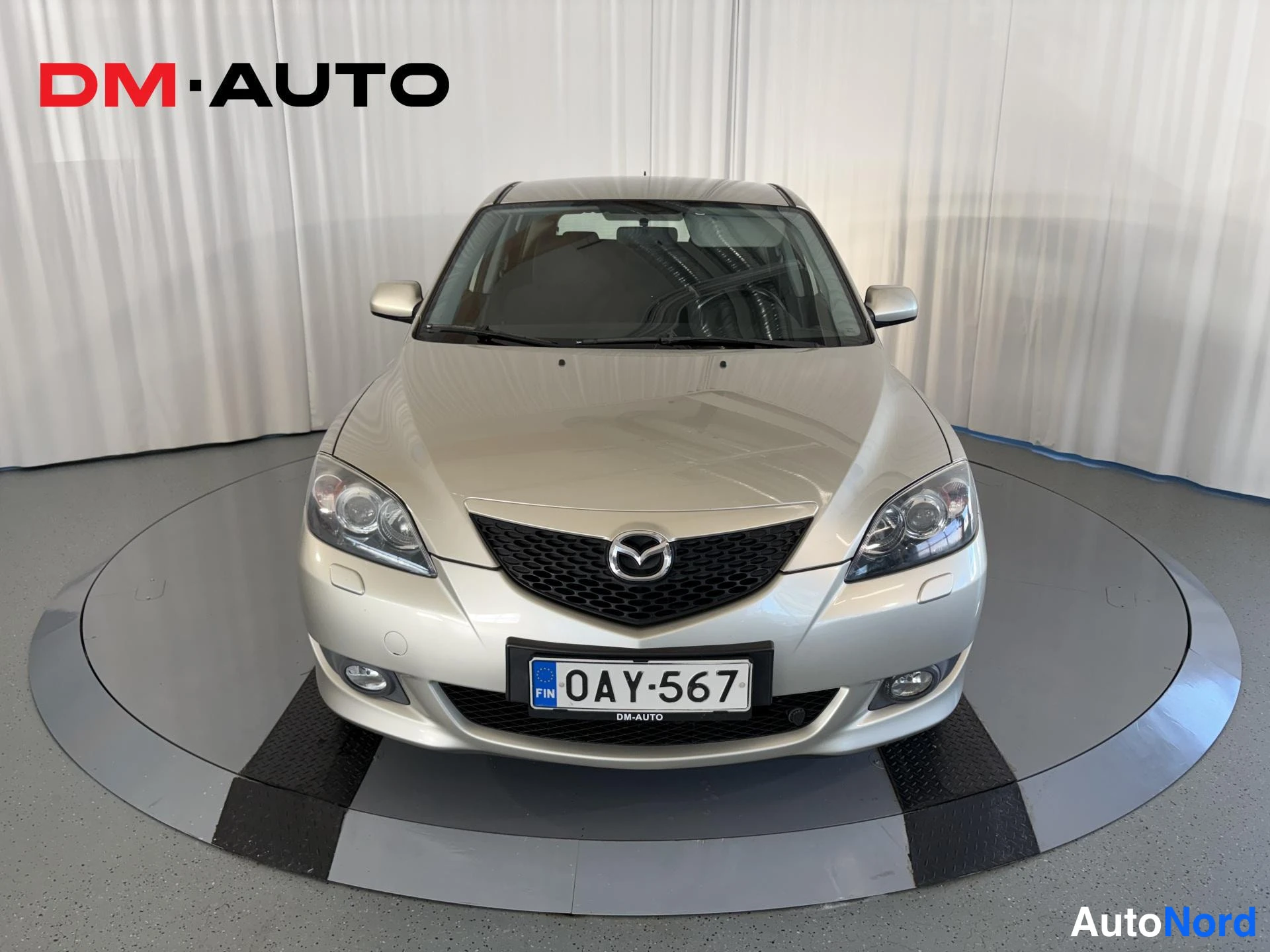 Edestä: Hopeanvärinen Mazda 3 suoraan edestä kuvattuna, rekisteritunnus.