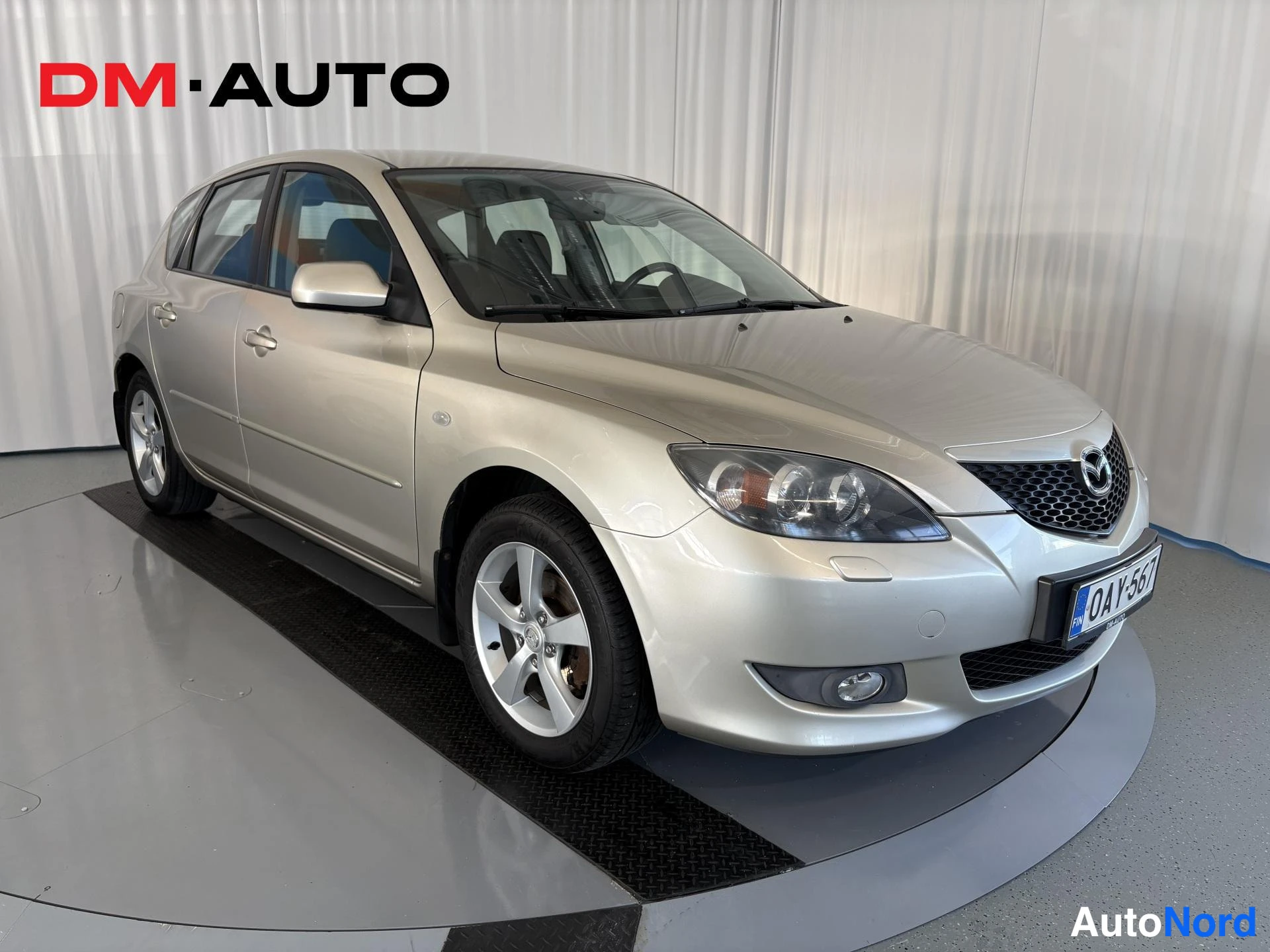 Etuviisto, nokka oikealle: Hopeanvärinen Mazda 3 -viistoperä etukulma oikealta, rekisteritunnus.
