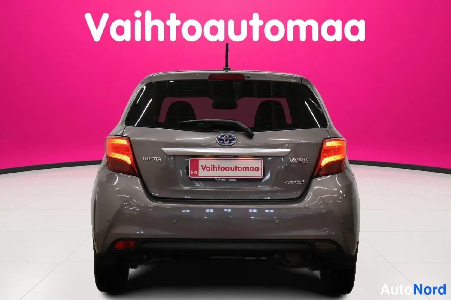 Takaa: Auton takanäkymä: Toyota Yaris-hybrid, takavaloja ja Takaluukun Toyota-merkki.