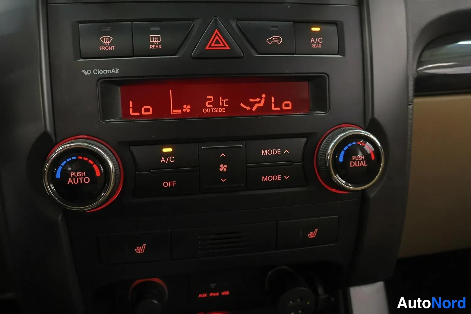 Muu: Ilmastointipaneeli punaisella näytöllä: Push Auto ja Push Dual -säätönupit, A/C-painike,_modes ja lämmitettyjen istuinten symbolit alhaalla.