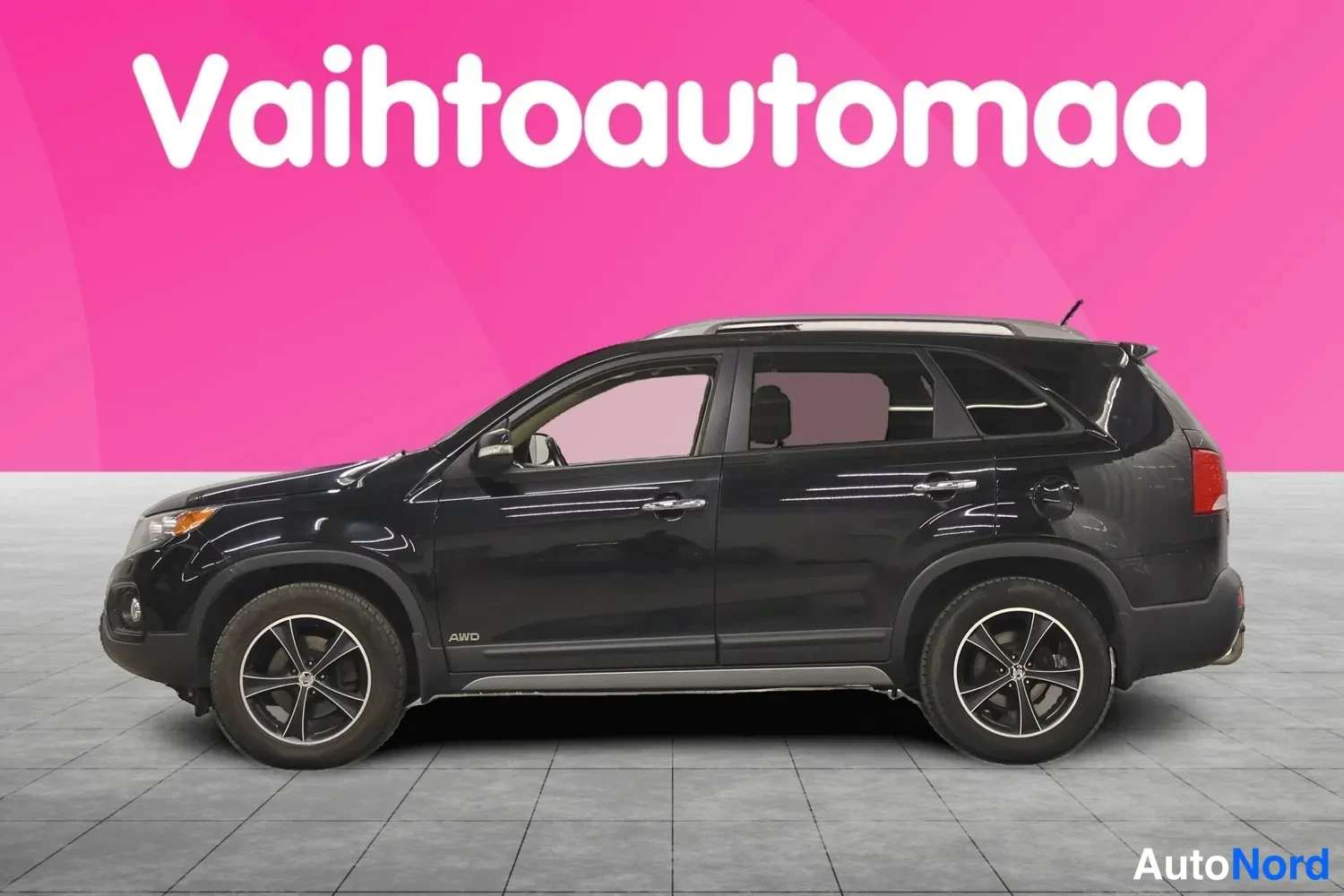 Etuviisto, nokka vasemmalle: Musta Kia Sorento -katumaasturi sivulta etukulmasta, hopeiset pyöränvanteet ja AWD-teksti ovessa.