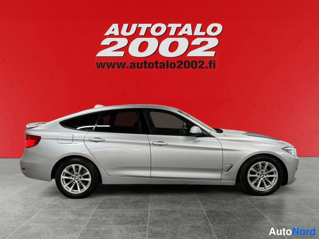 Sivulta: Sivuprofiilikuva hopeanvärisestä BMW 3 Gran Turismo -autosta punaisella taustalla.
