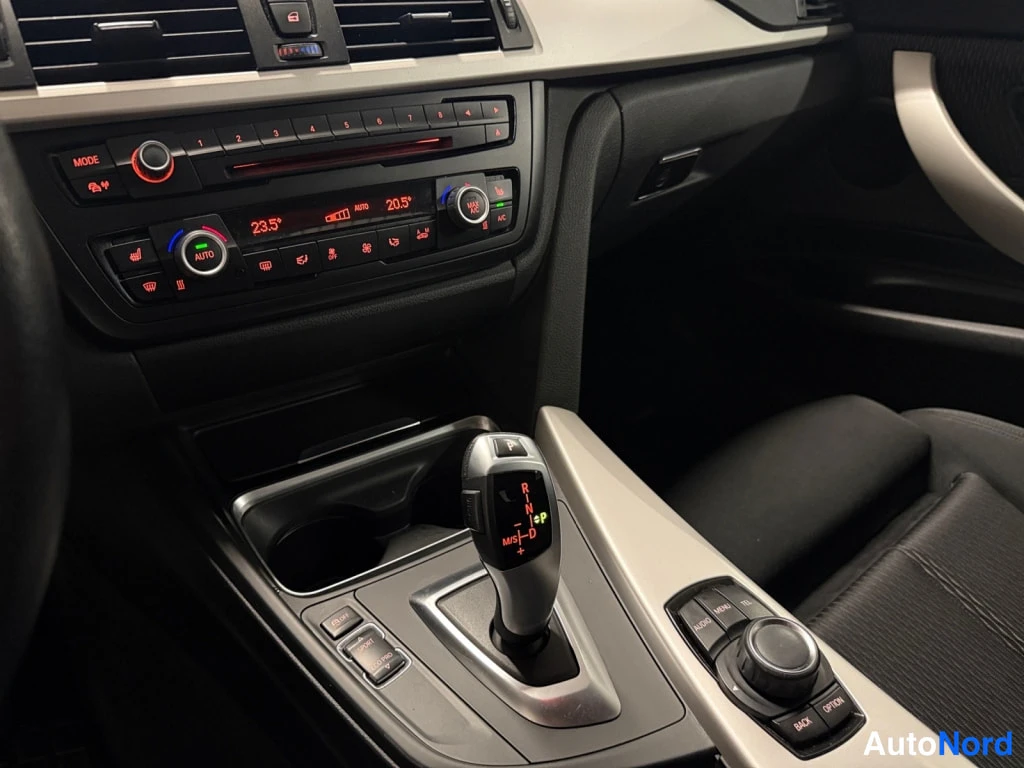 Muu: BMW:n kojelauta: automaattivaihteen valitsin (P R N D), kaksivyöhykkeinen automaattiilmastointi ja iDrive-ohjain nappien kanssa.