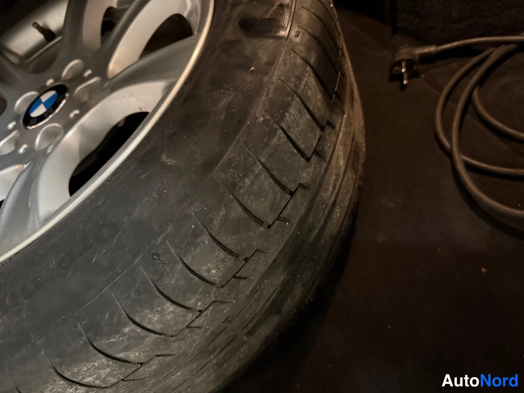 Muu: Vararengas hopeavanteella, jossa BMW:n logo, lähikuvassa; vieressä musta johto ja pistoke.