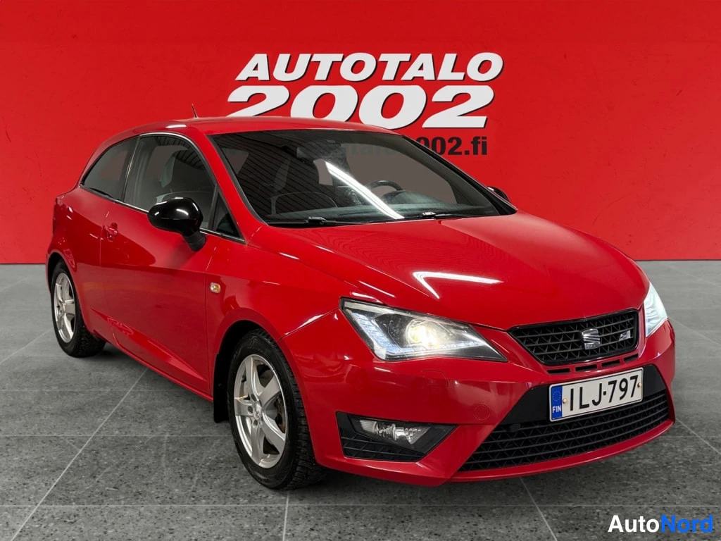 Etuviisto, nokka oikealle: Punainen Seat Ibiza SC kolmesta neljäsosasta edestä oikealta, rekisteritunnus, valkoiset vanteet.