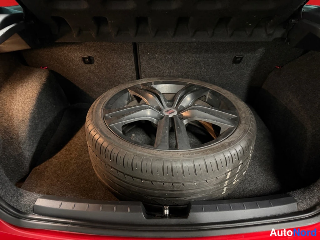 Muu: Seat Ibiza'n avattu tavaratila, jonka matolla seisoo ylimääräinen alumiinivannerrengas.