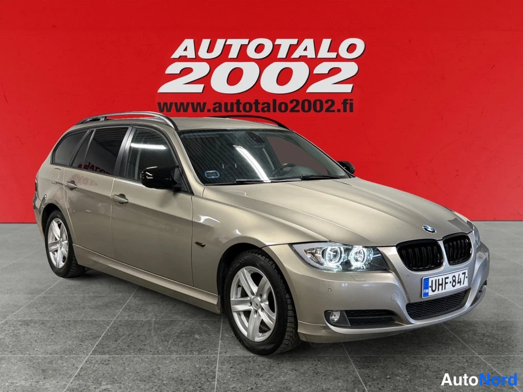 Etuviisto, nokka oikealle: Kultabevetä BMW 318 -farmariAuto etukulmasta, punainen tausta