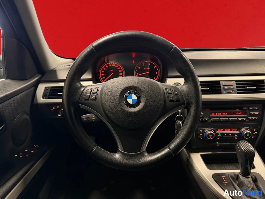 Muu: Ohjaamo kuljettajan puolelta: BMW-merkitty ohjauspyörä, mittaristo ja kojelauta automaattivaihteen valitsimella.