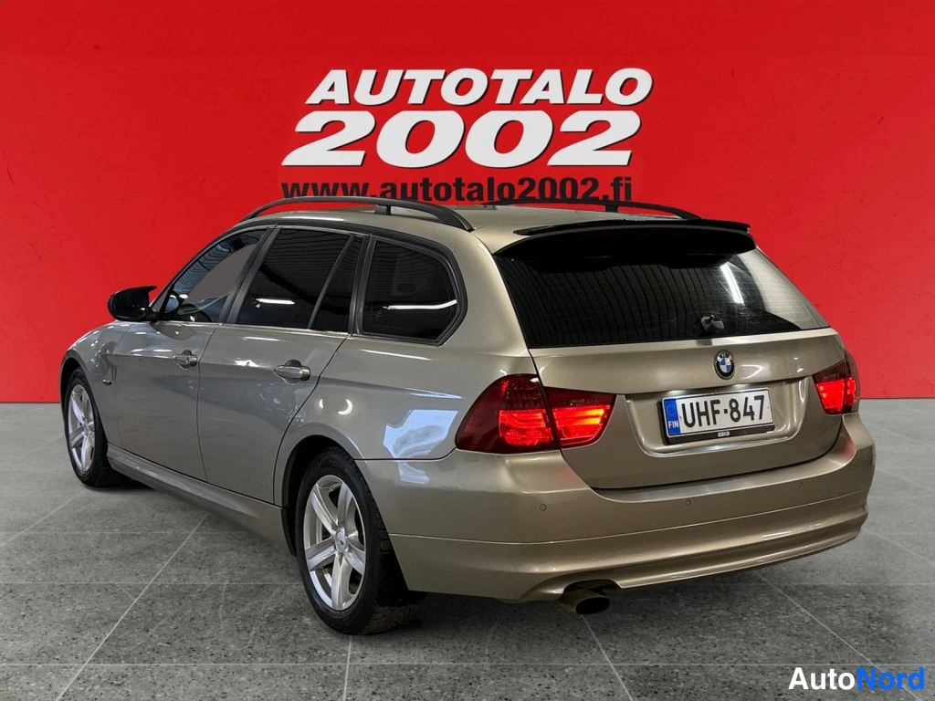 Takaviisto: Beige BMW:n takakulma: rekisterikilpi, takavaloja ja kattokaiteet.