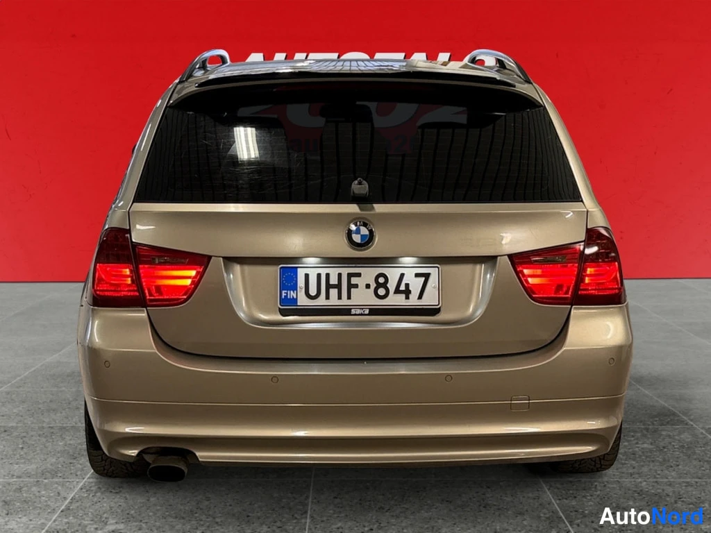 Takaa: Beige BMW:n takanäkymä suoraan takaa: rekisterikilpi, kattotelineet ja pakoputki.