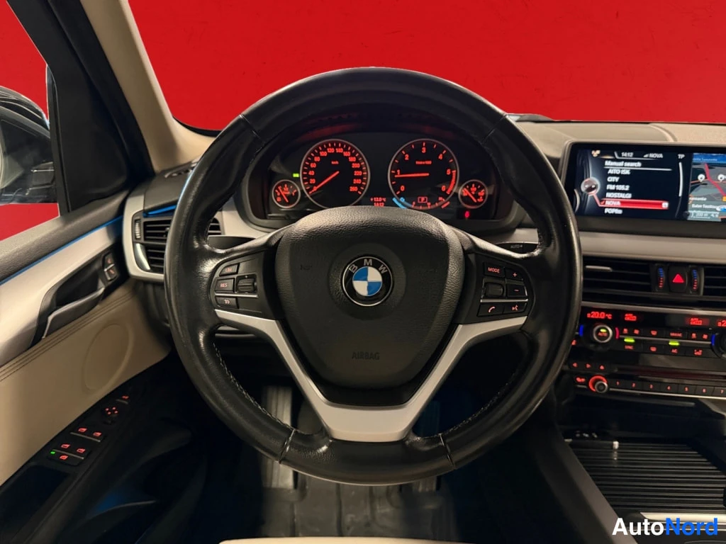 Yksityiskohta: BMW-ohjauspyörä, mittaristo ja kojelaudan näyttö punaisella taustalla