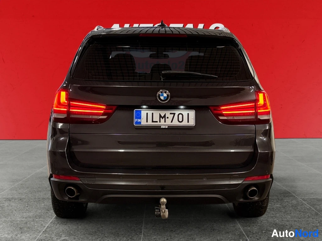 Takaa: Auton takanäkuva: tummanharmaa BMW X5, rekisterikilpi, kaksi pakoputkea