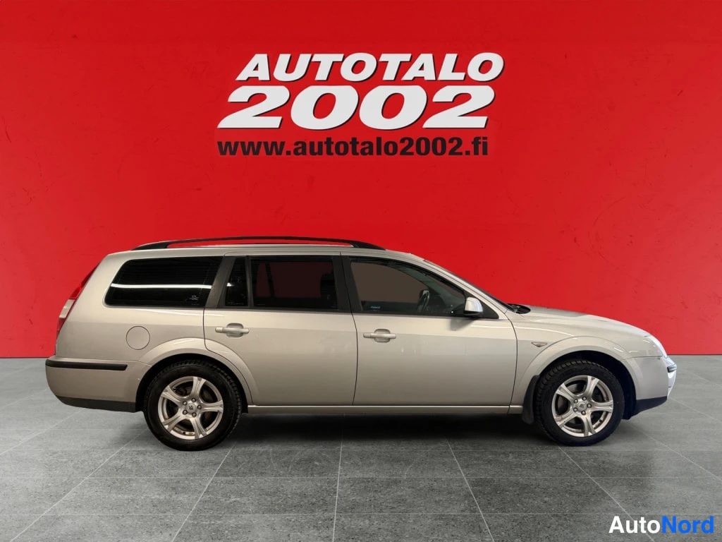 Sivulta: Hopeanvärinen Ford Mondeo -farmari sivukulmasta punaisella taustalla.