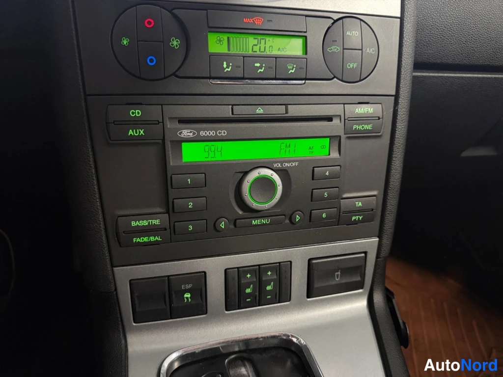 Edestä: Keskikonsolin paneli lähikuvassa: Ford 6000 CD -radionäyttö vihreällä näytöllä (n. 93.4 FM1), CD/AUX-napit ja automatic-ilmastointipaneeli (A/C, AUTO, OFF) 20,0