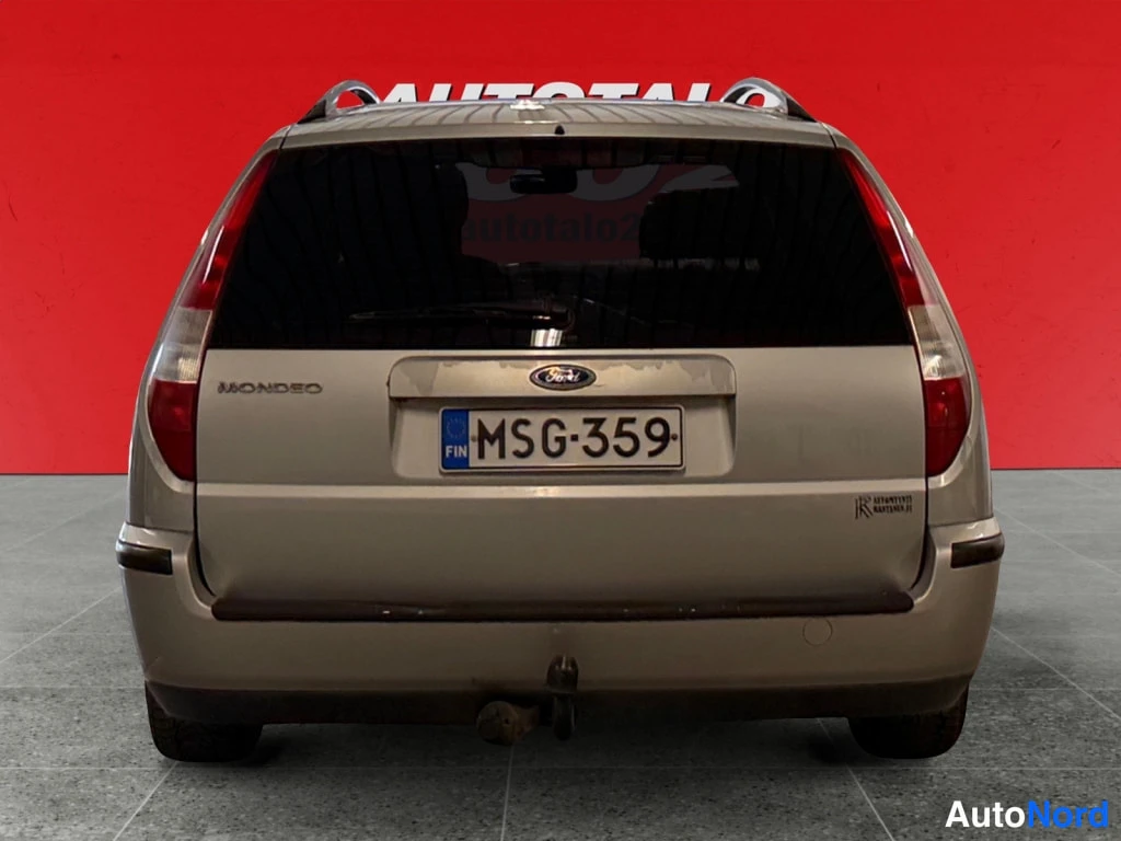 Takaa: Hopeanvärinen Ford Mondeo -asema-auto suoraan takaa, Mondeo-tunnus, rekisterikilpi ja vetokoukku näkyvät.