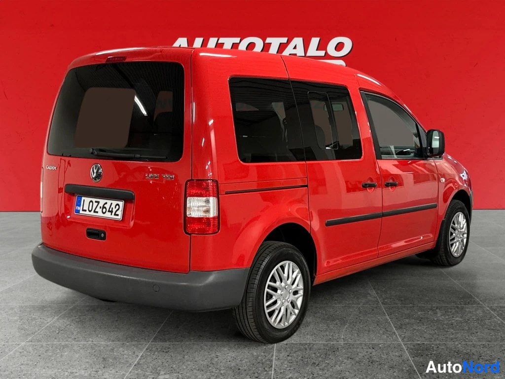 Takaviisto: Punainen Volkswagen Caddy takakolmasosa kuvattuna takaa vasemmalta, rekisterikilpi ja Caddy-merkintä takaluukussa.