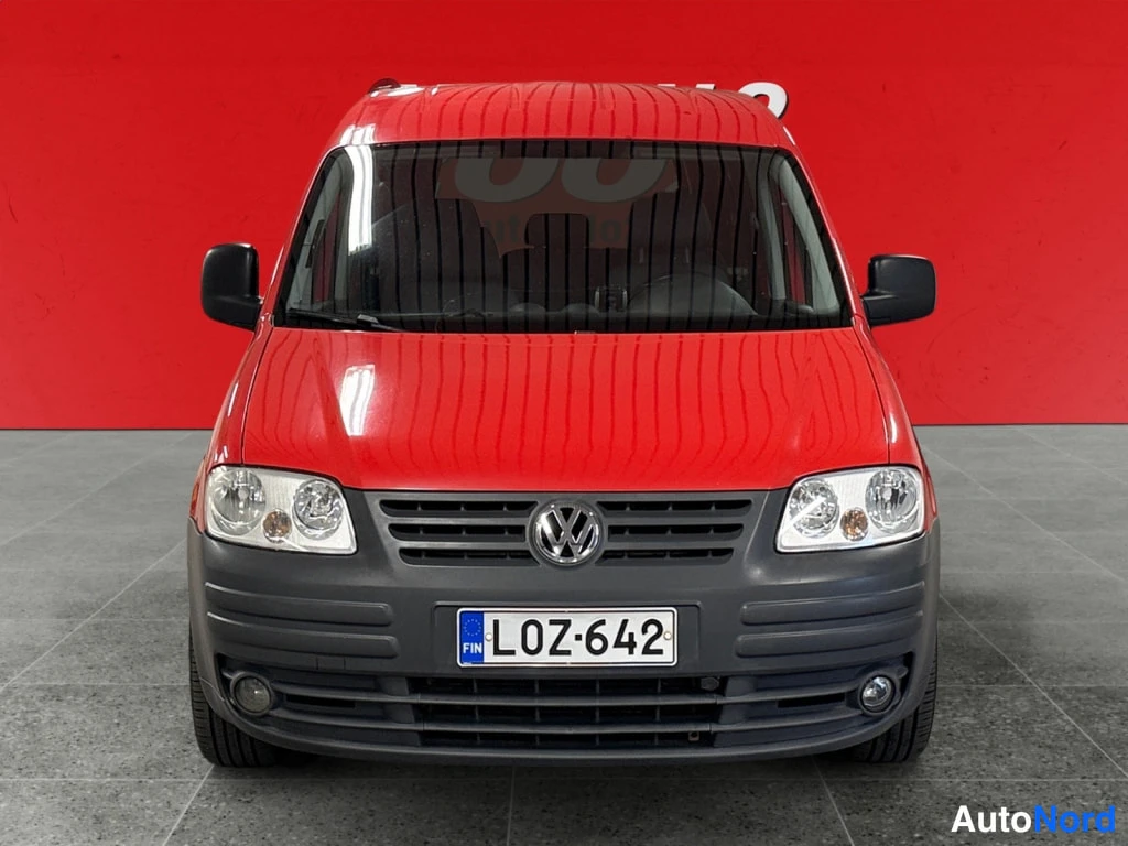 Edestä: Punaisen Volkswagen Caddy -auton keulakuva suoraan edestä, rekisterikilpi.