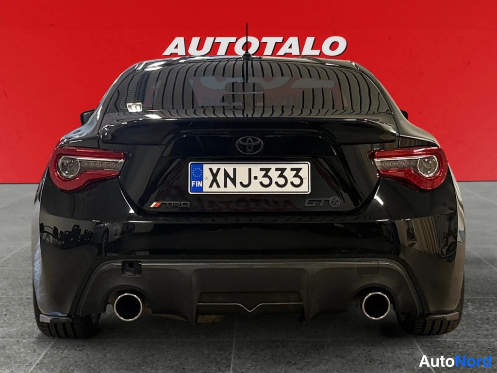Takaa: Mustan Toyota GT86:n takanäkymä, rekisterikilpi, TRD- ja GT-koristeet, kaksi pakoputkea.