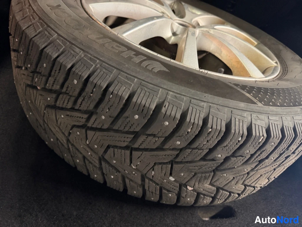 Yksityiskohta: Nastarengas vanteella lähikuvassa; sivuseinässä Goodyear-teksti ja nokit näkyvissä.