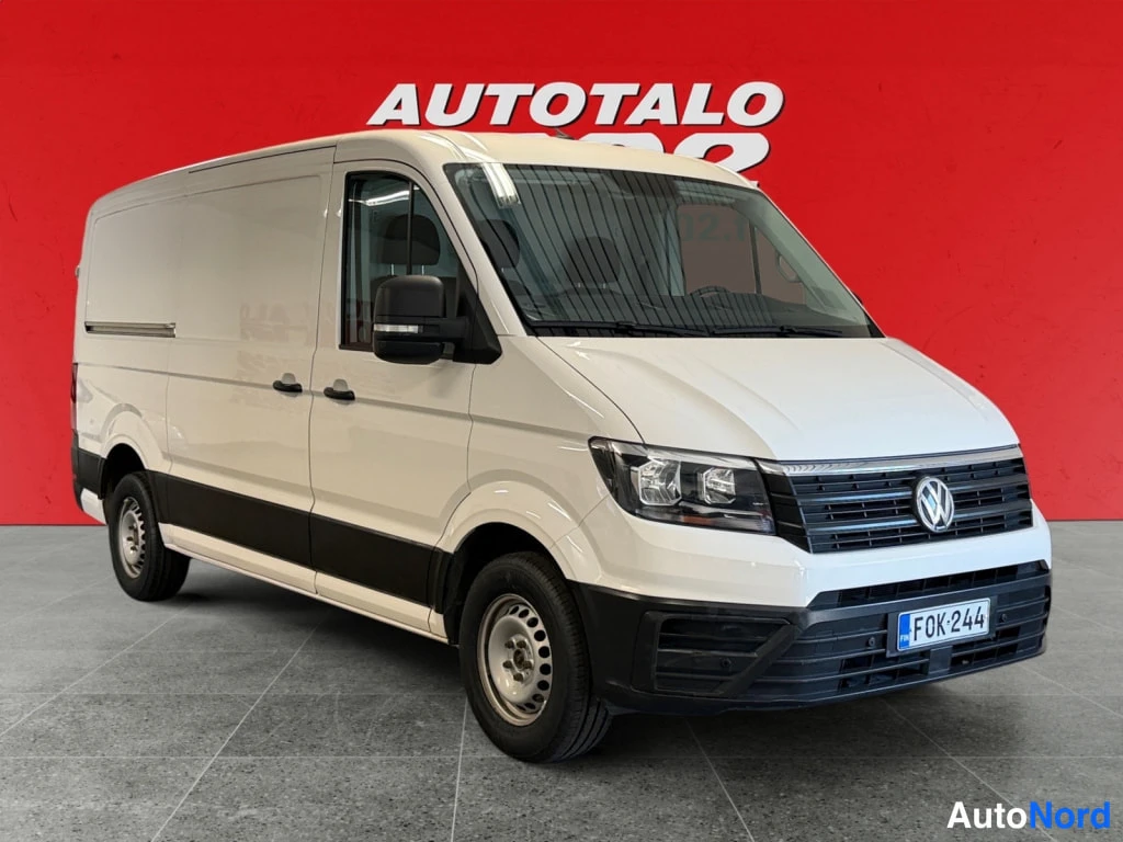 Etuviisto, nokka oikealle: Valkoinen Volkswagen Crafter -pakettiauto kolmeneljännesnäkymässä edestä oikealta, rekisteritunnus.