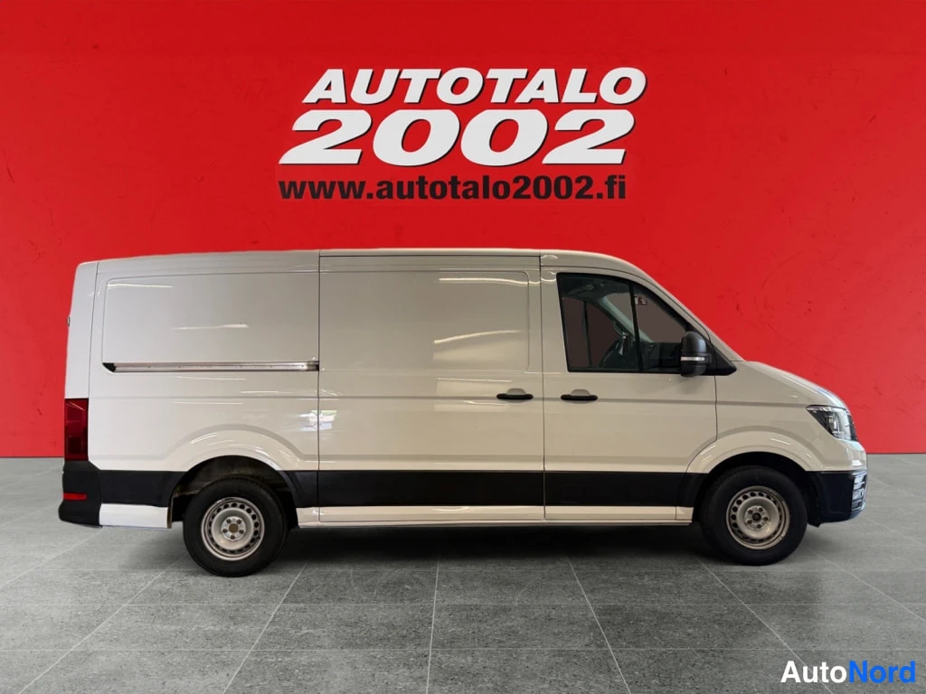 Sivulta: Valkoinen Volkswagen Crafter -pakettiauto sivulta, pitkä ahtopeli ja liukuno oven kaista etupyörän takana.