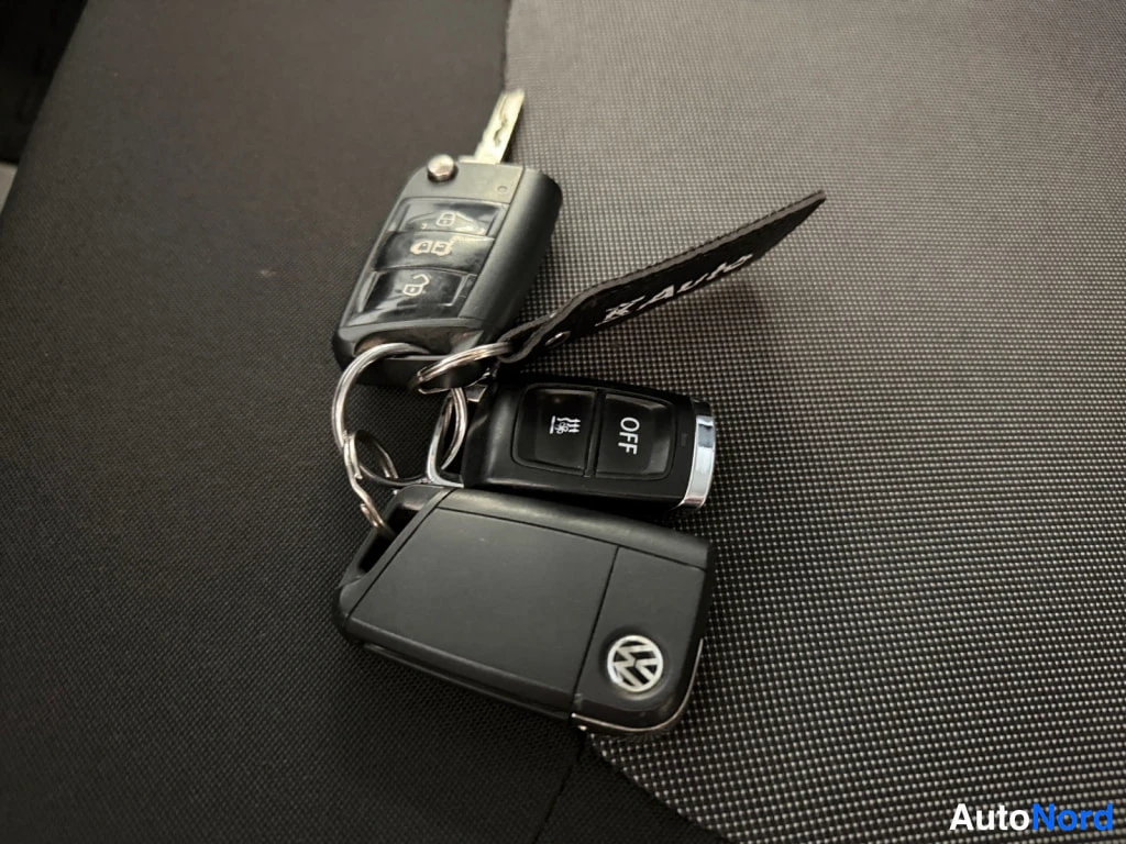 Etuviisto, nokka oikealle: Kolme avainnippua tummalla kankaalla: Volkswagen-avain, kauko-ohjain OFF-painikkeella ja avainranneke