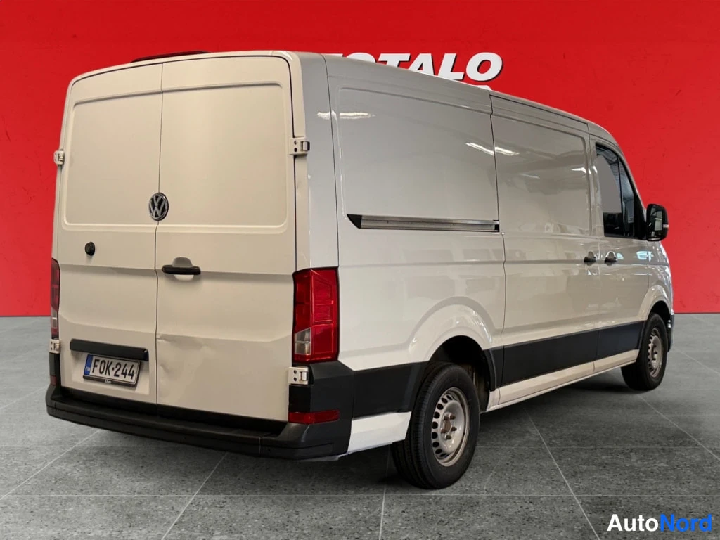Takaviisto: Valkoinen Volkswagen Crafter -pakettiauto takaa oikealta, kaksi takapuuta ja rekisteritunnus.