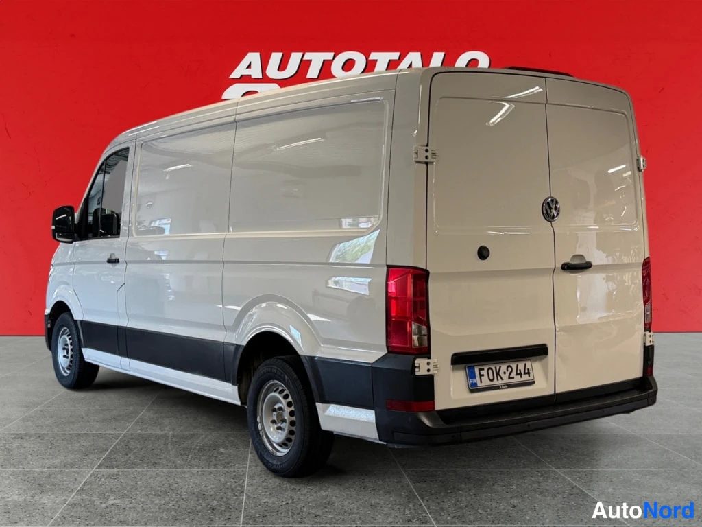 Takaviisto: Valkoinen pakettiauto takakulmassa, rekisteritunnus, punainen tausta.