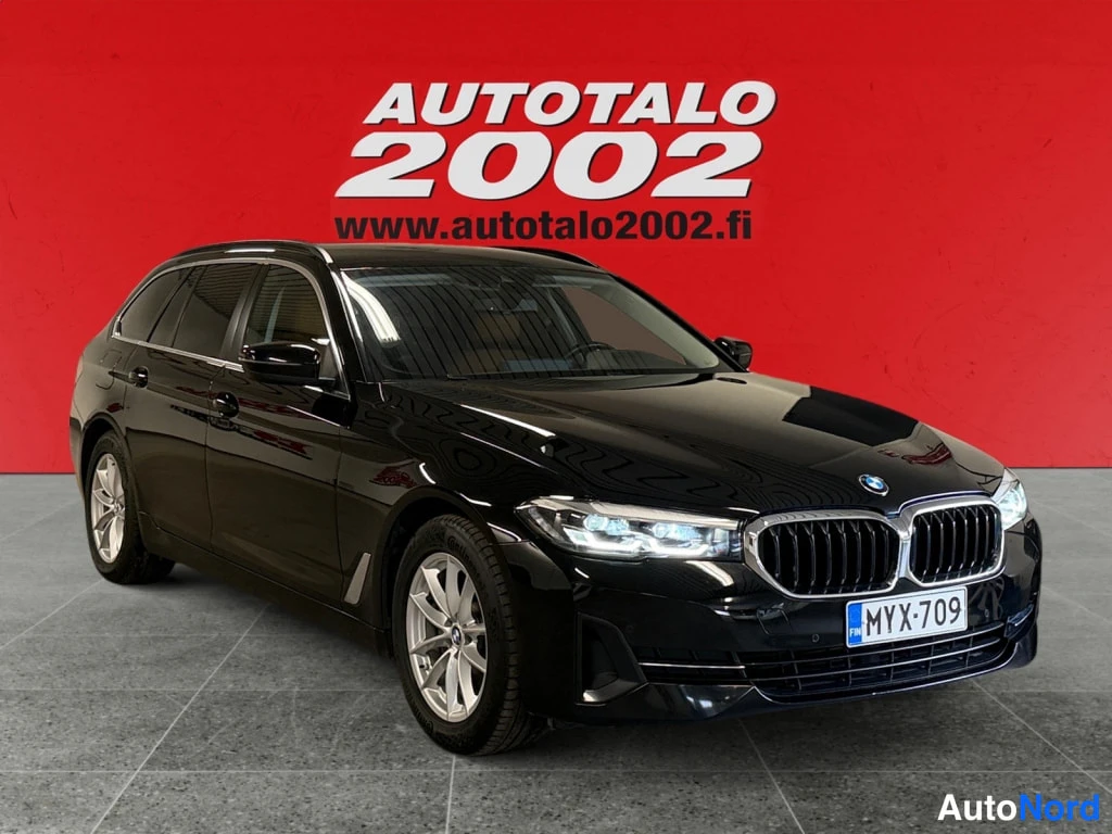 Etuviisto, nokka oikealle: Musta BMW 5 -sarjan farmari, etukolmasosa oikealta, rekisteritunnus.