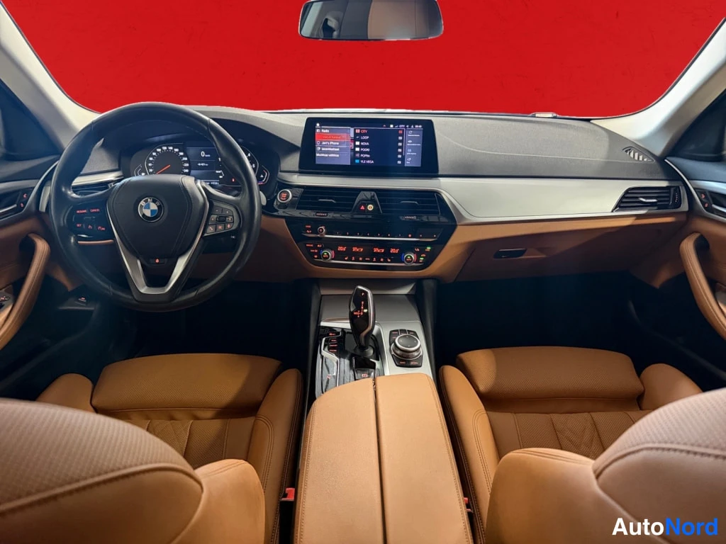 Yksityiskohta: Kohtisuora näkymä kojelautaan: monitoimiohjauspyörä BMW-embleemillä, digitaalinen mittaristo, keskikäytön infotainment-näyttö ja automaattivaihteen valitsin.