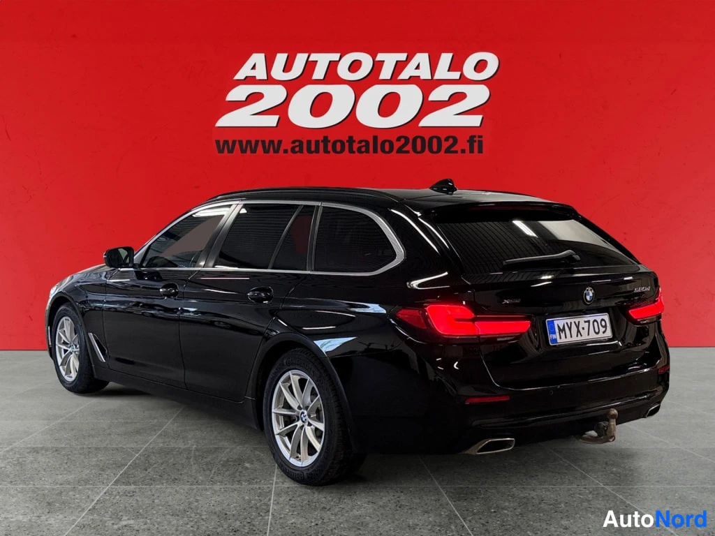 Takaviisto: Musta BMW 520 -farmari takaa oikeasta kolmasosanakulmasta, rekisteritunnus, punainen tausta.