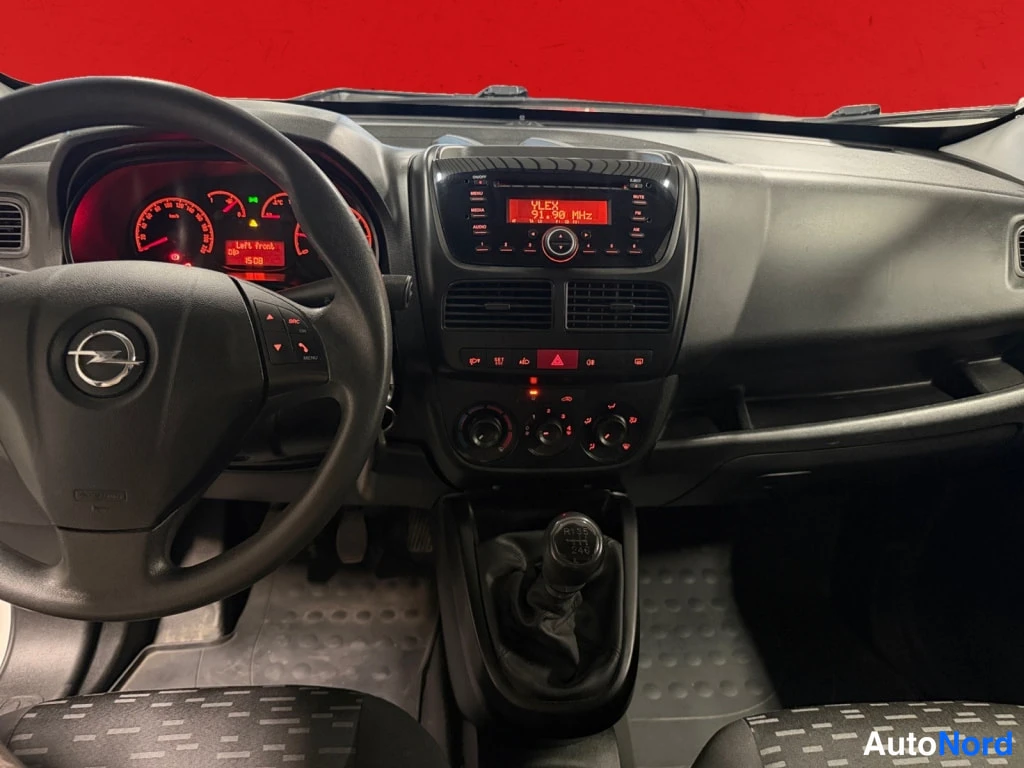 Yksityiskohta: Kojelaudan näkymä: Opel-ohjauspyörä, analogiset mittarit, radio jonka näytössä lukee YLEX 31.90 MHz, käsivaihteisto ja tummat matot.