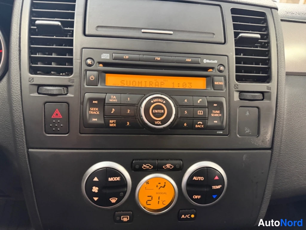 Muu: Nissan Tiidan kojelaudan keskuspaneeli: radio- ja ilmastointipainikkeet, Bluetooth ja lämpötilanäyttö.