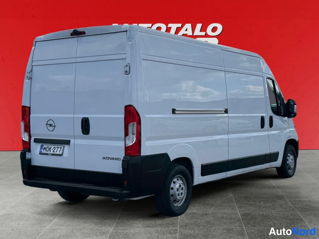 Takaviisto: Valkoisen Opel Movano -pakettiauton takakulmanäkymä, takavalot, Opel-merkki, rekisterikilpi ja Movano-teksti näkyvät.