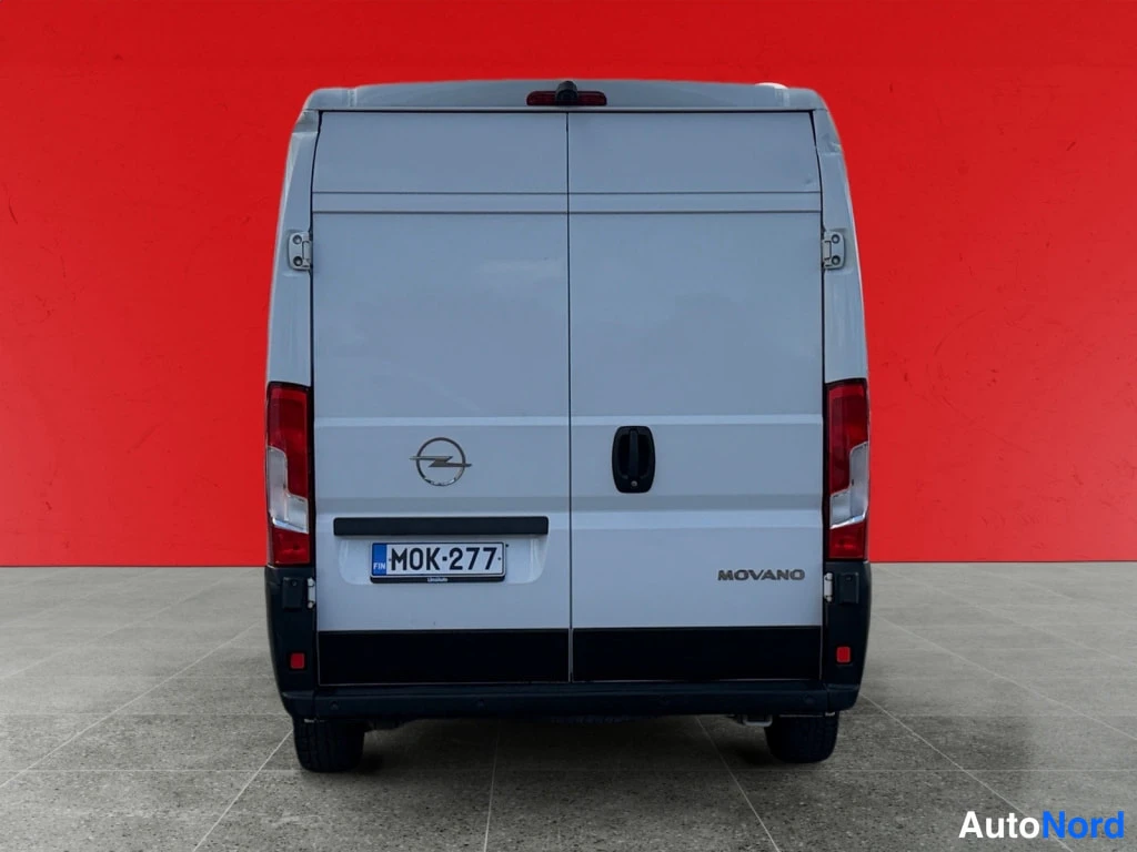 Takaa: Opel Movano -pakettiauton takaosa, valkoinen kori, rekisterikilpi, punainen taustaseinä.
