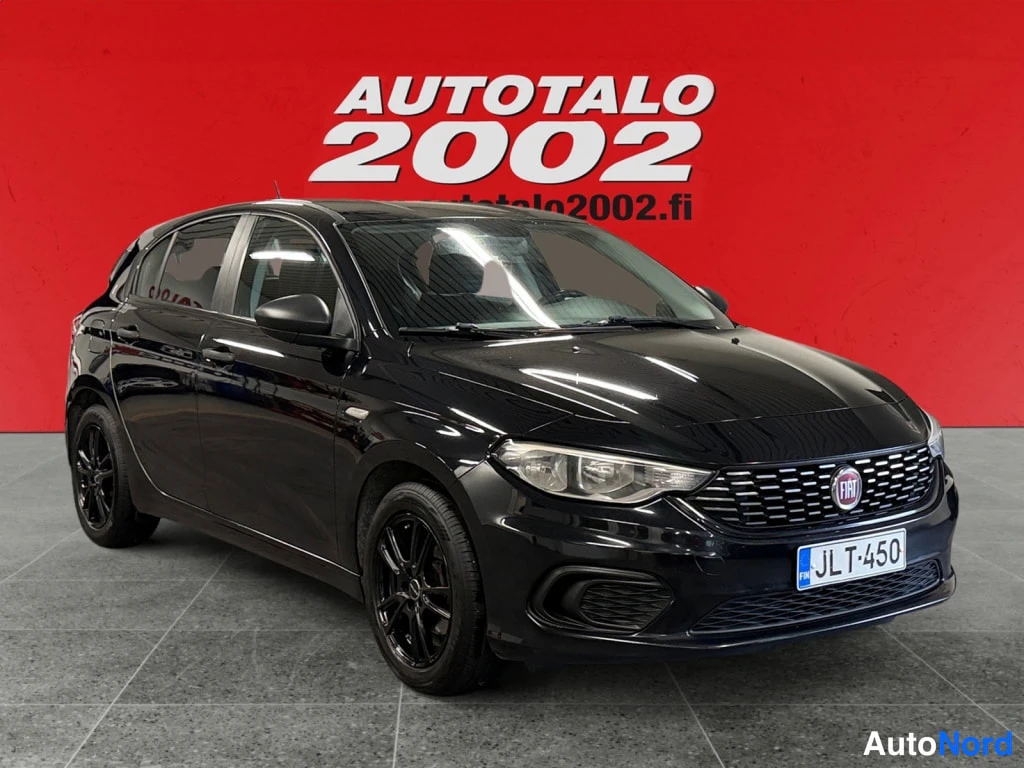 Etuviisto, nokka oikealle: Mustan Fiat Tipo -henkilöauton etukulma, etusäleiköt, fi-merkillä, mustat vanteet, rekisterikilpi.