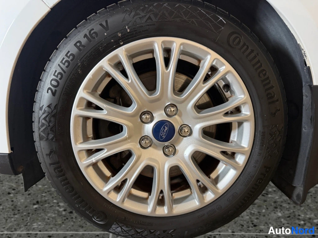 Yksityiskohta: Auton pyörä lähikuvassa: hopeinen vanteen pölyllinen Ford-keskiökorkki, Continental-renkaita, kyljessä näkyy merkintä 205/55 R 16 V.