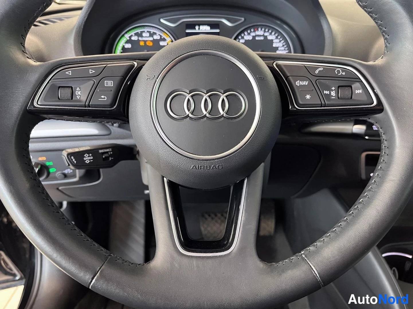 Edestä: Monitoimiohjauspyörän lähikuva, Audi-logo ja NAV- ja ääninäppäimet näkyvissä.