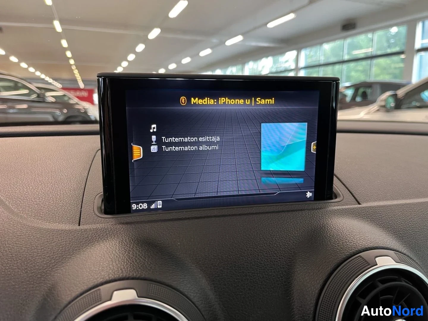 Muu: Auton kojelaudan infotainment-näyttö näyttää medialähteenä Bluetooth-yhteydellä yhdistettyä iPhonea (Sami), teksti 'Media: iPhone u | Sami' sekä 'Tuntematon esi