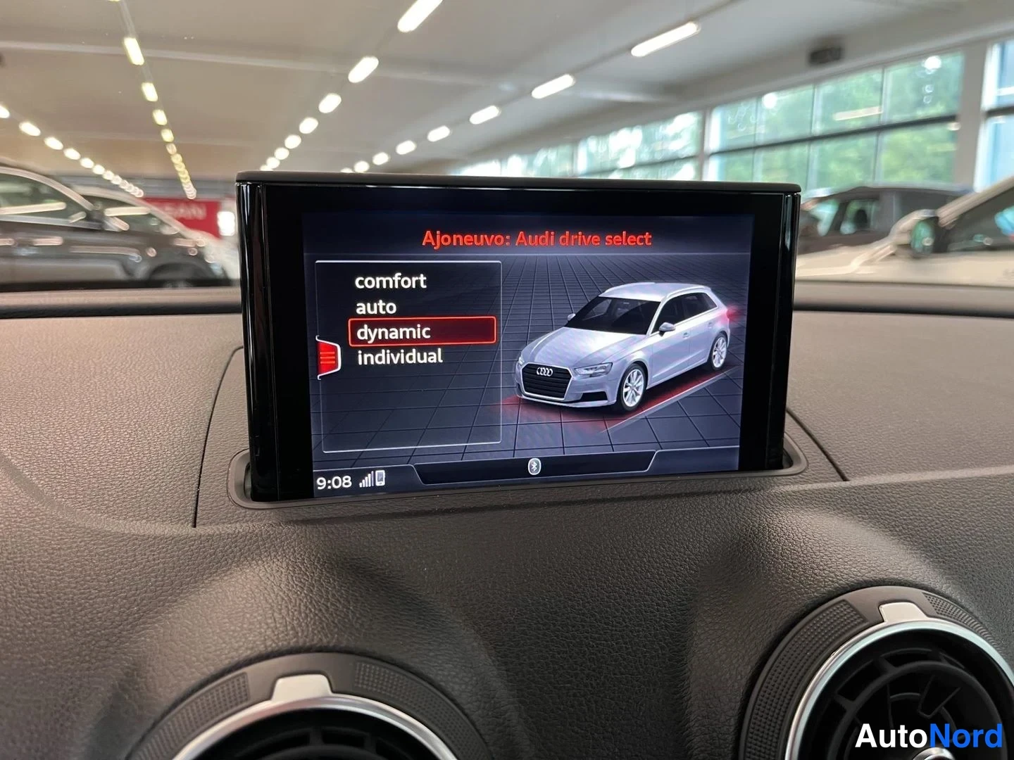 Muu: Kojelaudan näyttö valikossa 'Ajoneuvo: Audi drive select' vaihtoehdoilla comfort, auto, dynamic ja individual; dynamic korostettuna. Hopeisen Audi A3:n kuva näy