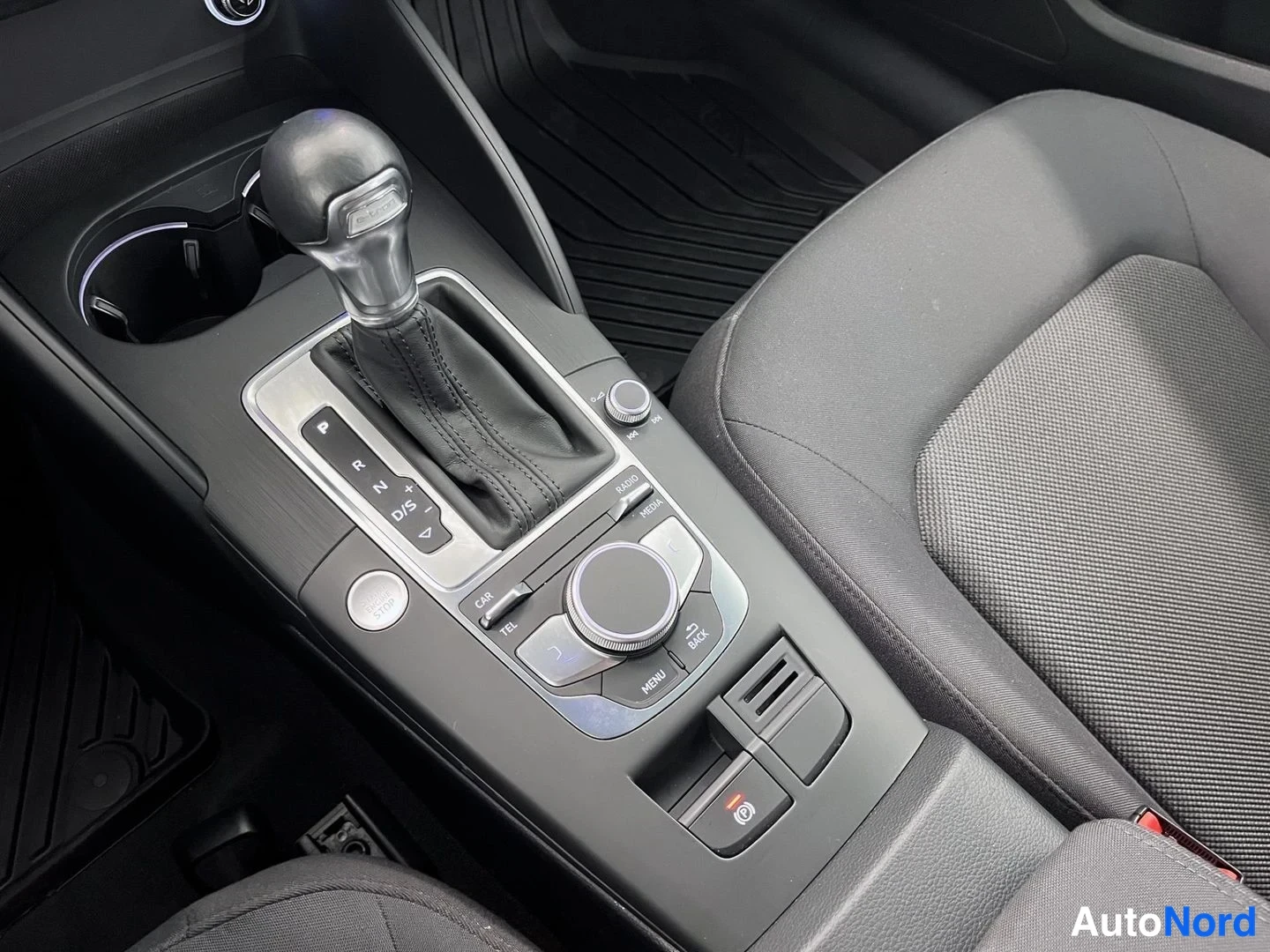 Muu: Audi A3:n vaihteenvalitsin P-R-N-D/S-merinnöillä, MMI-ohjainnuppi (RADIO, MEDIA, CAR, TEL, MENU, BACK) ja nappilukitus, istuimen ja maton vieressä.