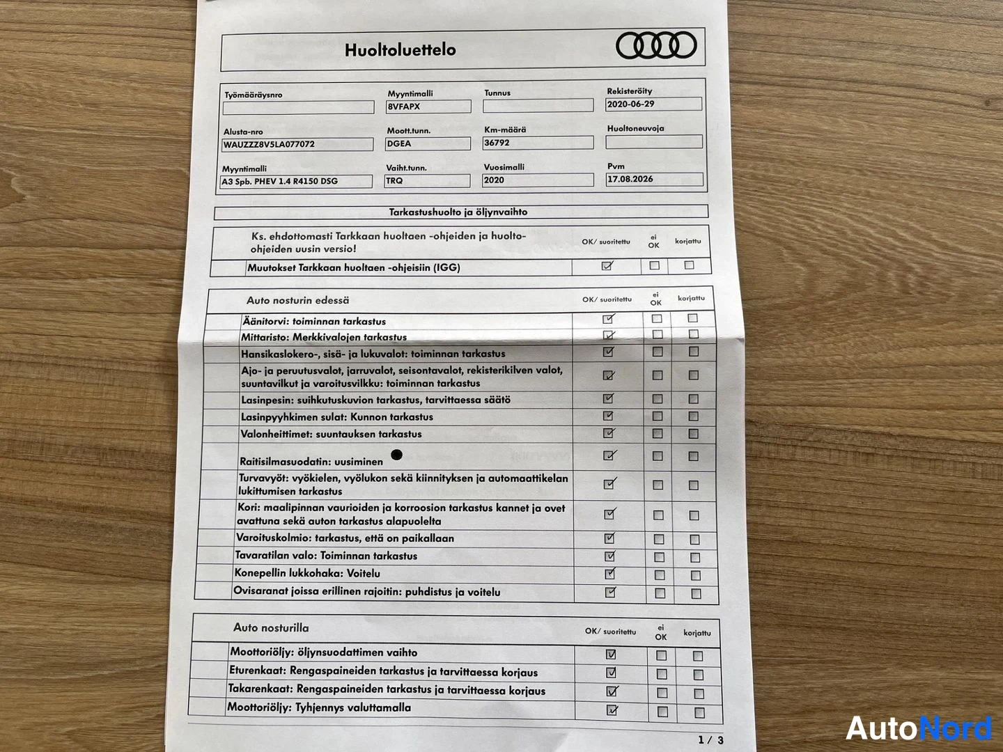 Asiakirja: Audi-huoltoluettelo puupöydällä, jossa merkintöjä tarkastushuollosta: Malli A3 Spb. PHEV 1.4 R4130 DSG, vuosimalli 2020, km-määrä 36792.