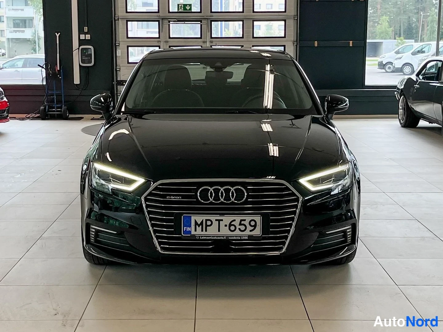 Edestä: Mustan Audi A3:n etunäkymä e-tron-merkinnällä, LED-etuvaloilla ja rekisterillä.