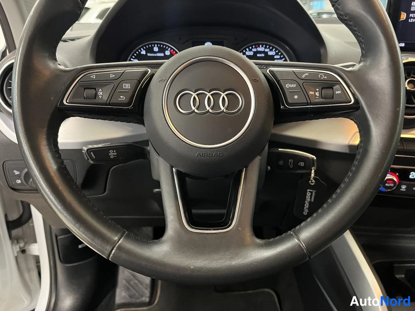 Muu: Lähikuva Audi-ohjauspyörästä: puhelin- ja navigointipainikkeet, AIRBAG-teksti ja avaimenperä, jolla lukee Laakianauto.