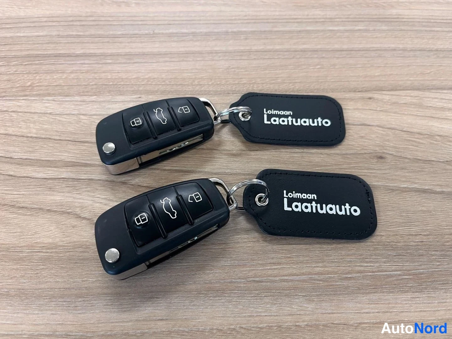Muu: Kaksi Avaimet paarikaarilla, otsikossa mustan tekstilaput kunnossa 'Loimaan Laatuauto', avaimet mukautettuina tukevina koodisavupunaisina palkeina.